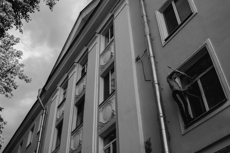 A monochrome photo showing a man cleaning windows on a tall building with a squeegee.